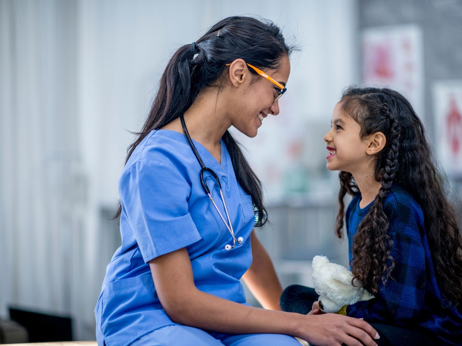 Healthcare professional talking with a child in a clinical setting.